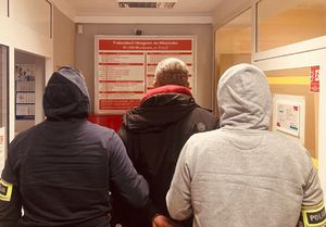 Policjanci stoją z zatrzymanym w prokuraturze