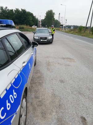 policjantka dokonuje kontroli pojazdu w rejonie przejazdu kolejowego