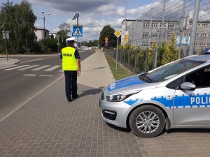 Policjant sprawdza oznakowanie w rejonie szkoły