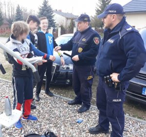 Policjanci przekazują uczniom elementy odblaskowe w pobliżu szkoły