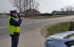 Policjant mierzy prędkość pojazdu na drodze