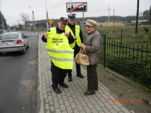 Policjanci przekazują pieszej kamizelkę odblaskową