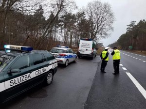 Policjant wspólnie z funkcjonariuszem SAK stoją przy drodze w trakcie wspólnych działań