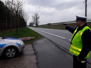 Policjant mierzy prędkość pojazdu na drodze