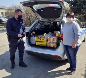 Policjant przekazuje pracownicy schroniska zakupioną karmę