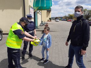 Policjanci i strażnicy przekazują kamizelki odblaskowe pieszym