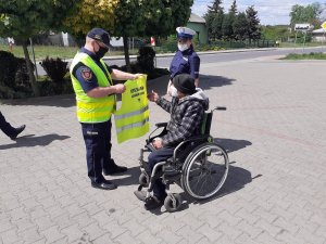 Policjanci i strażnicy przekazują kamizelki odblaskowe pieszym