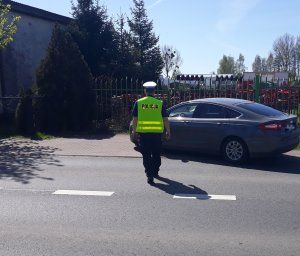 policjant idzie do zatrzymanego pojazdu celem kontroli