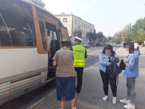 Policjant wchodzi do autobusu na przystanku i kontroluje czy pasażerowie mają maseczki