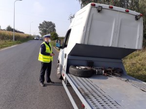 Policjant w trakcie kontroli pojazdu stoi przy drzwiach od kierowcy i z nim rozmawia