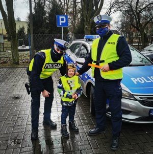 policjanci wręczają kamizelkę dziecku