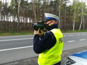 Policjant sprawdza na drodze prędkość za pomocą urządzenia do pomiaru