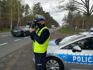 policjant sprawdza prędkość kierujących na drodze krajowej