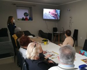 policjantka pokazuje seniorom film profilaktyczny