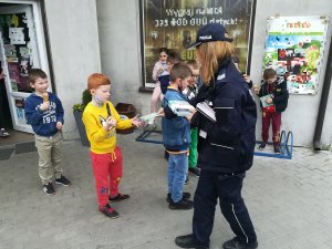 policjantka rozdaje dzieciom książeczki