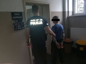 policjant wprowadza zatrzymanego do pokoju