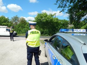 policjant stoi na drodze, kontroluje pojazdy