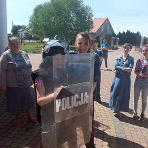 policjantka pomaga przymierzyć uczestnikowi spotkania kask policyjny
