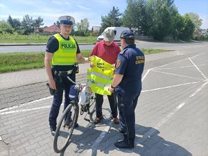 policjanci wręczają kamizelkę rowerzyście