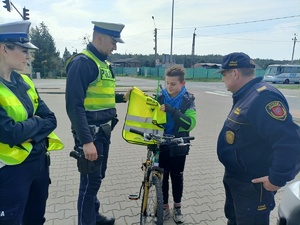 policjant wręcza kamizelkę odblaskową dziecku
