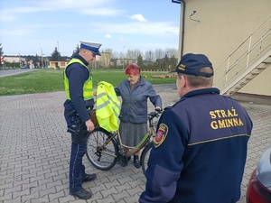 policjant wręcza kamizelkę odblaskową kobiecie