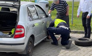 policjant wymienia oponę kierowcy