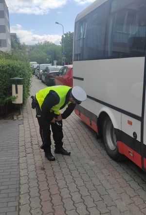 policjant sprawdza ogumienie autokaru