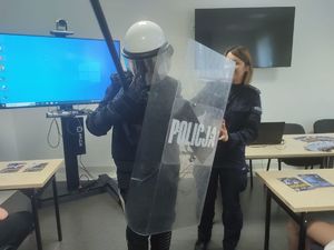 policjantka pomaga uczniowi przymierzyć element umundrowania