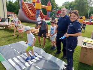 dziecko przechodzi przez matę z pasami pod okiem policantki