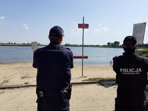 policjanci stoją na plaży i obserwują