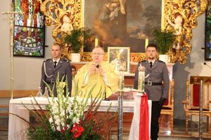 ksiądz przy ołtarzu w asyście policjatów