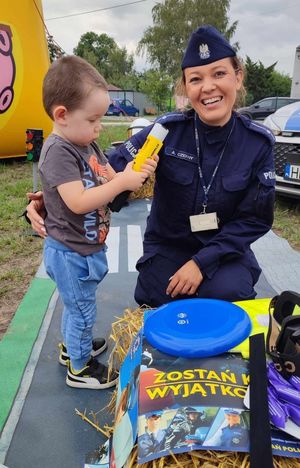 Policjantka stoi z małym chłopcem który trzyma sprzęt do badania stany trzeźwości