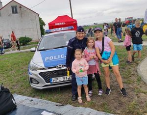 Policjantka z dziećmi stoi przed radiowozem