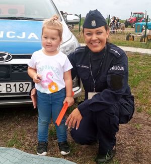 policjantka z małą dziewczynką stoi przy radiowozie