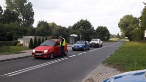 Policjant stoi na ulicy bada stan trzeźwości zatrzymanych kierujących pojazdami