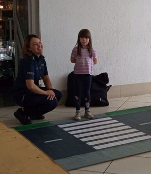 policjantka  z dziewczynką na macie drogowej