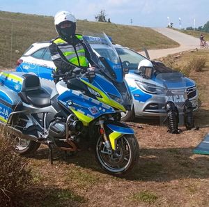 Policjant na motorze, obok radiowóz policyjny