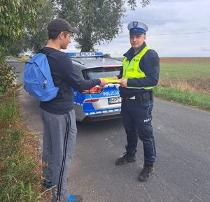 policjant przekazuje kamizelkę młodemu mężczyźnie