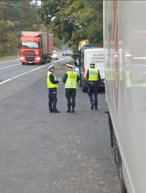 policjant i inspektor kontrolują pojazd