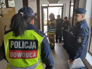 policjanci rozmawiają ze strażakami w budynku szkoły