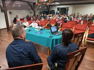 dzielnicowi siedzą na krzesłach w tle uczestnicy debaty