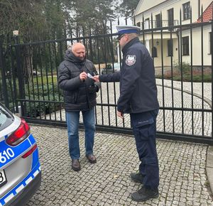 policjant daje pieszemu ulotkę