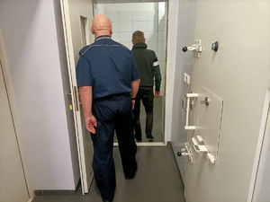 policjant wprowadza zatrzymanego do pomieszczenia dla zatrzymanych