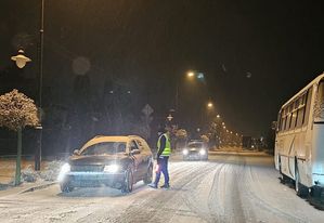 policjant stoi przy samochodzie w trakcie kontroli, duże opady śniegu