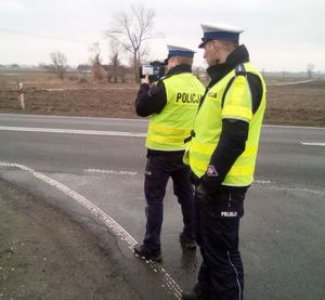 policjanci stoją na drodze jeden z nich trzyma miernik pomiaru prędkości