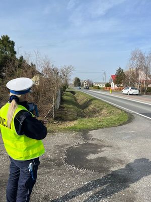 policjantka stoi z miernikiem prędkości na drodze