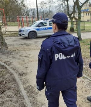 policjantka obserwuje park, w tle radiowóz