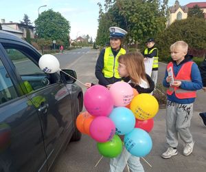 dziewczynka wręcza balon kierowcy pojazdu obok stoi policjantka