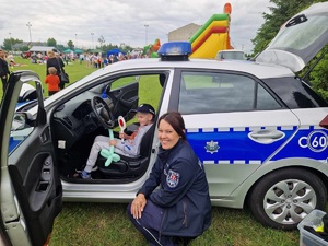 policjantka przykuca przy dziecku, które siedzi w radiowozie