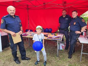 strażnik i policjant wręczają balona chłopcu